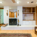 Interior view of a white brick fireplace and custom wood-paneled built-ins in a Southfield mid-century ranch.