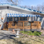 Private backyard deck with a blue and white striped awning on a brick ranch home in Southfield, Michigan.