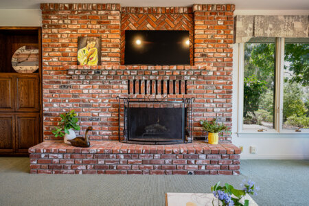Living room with brick fireplace, staged seating, and natural light at the Fallbrook OPen House at 145 Yucca Rd Fallbrook.