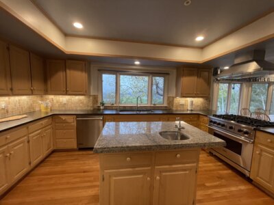Kitchen and dining area at 145 Yucca Road with island, gas cooktop, and windows looking out to trees on a rainy day.